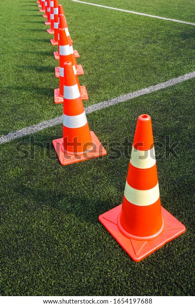 Orange cones\
arranged in an outdoor\
stadium.