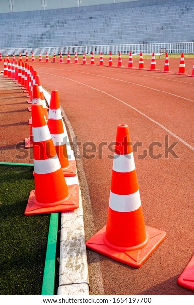 Orange cones\
arranged in an outdoor\
stadium.