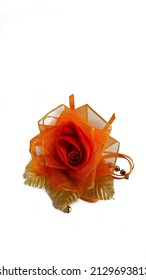 An orange corsage flower made of glass filament fabric. A corsage is a small flower-shaped accessory that is pinned to the collar of a woman's clothing or tied around her wrist.