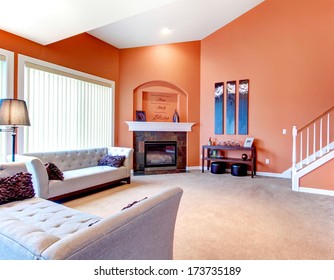 Orange Cozy Living Room With Carpet Floor, White Wood Stairs, Grey Furniture And Fireplace. Decorated Table With Candles And Wood Wall Handmade Art