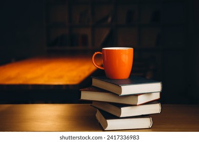 An orange cup on a stack of books on a dark library background. Book background. Education, learning and reading concept. Copy space. - Powered by Shutterstock