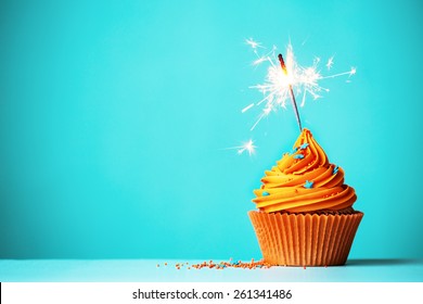 Orange cupcake with sparkler and copy space to side