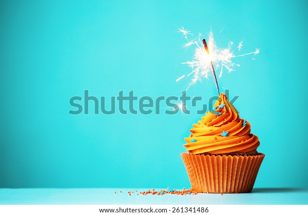 Orange\
cupcake with sparkler and copy space to\
side