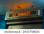An orange digital train display reads "NJ Transit" on one of the system