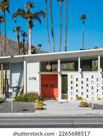 Orange door at mid-century house with cinder blook white wall 