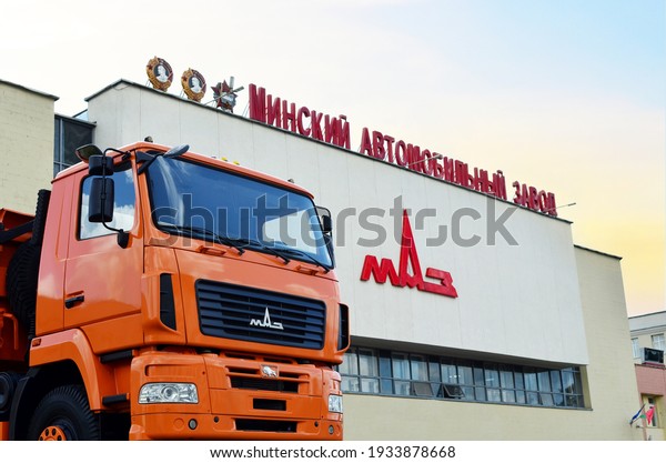 Orange dump truck MAZ\
at the building of the plant of the Minsk Automobile Plant where\
trucks and buses are produced. Heavy industry of Belarus. Minsk,\
Belarus, 03.10.2021