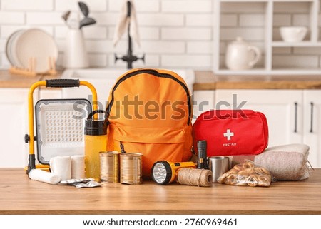 Orange emergency backpack with necessities on table in kitchen