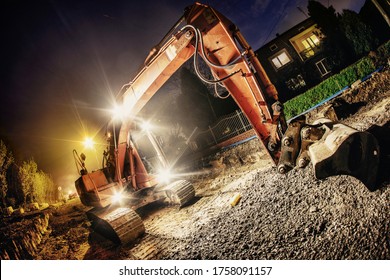 Orange excavator digger working at night on the street