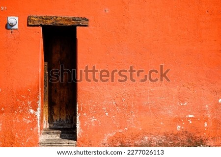 orange facade of a house with a sign on it, wooden door, colorful mayan house