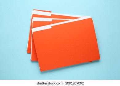 Orange files with documents on light blue background, top view