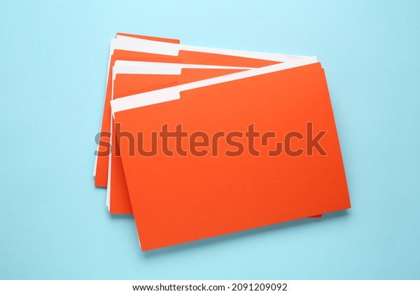 Orange files with documents on light blue\
background, top view