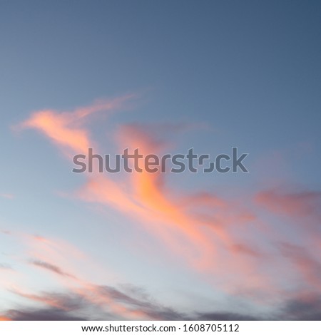 An orange firely cloud whisp on a blue sky.