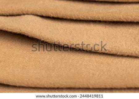 orange fleecy fabric is part of a garment, part of a raincoat made of beige material with a short pile
