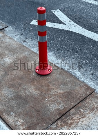 Orange flexible delineator post installed on a road
