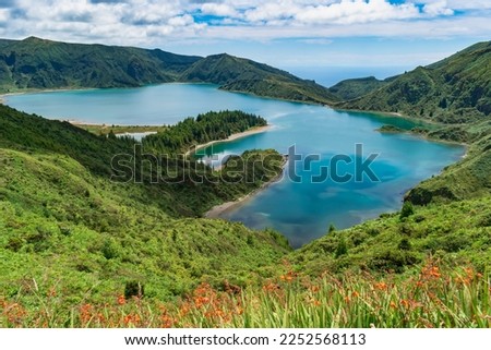Orange flowers and green vegetation on the hill to the volcanic caldera and aerial view of Fire Lagoon, São Miguel - Azores PORTUGAL
