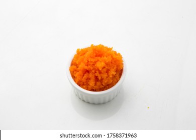 Orange flying fish egg roe in a small ceramic white cup isolated white background