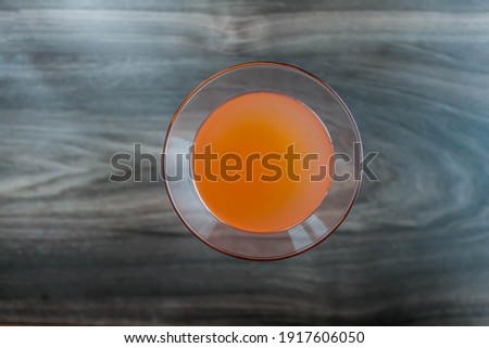 Orange fresh coctail juice in glass up view on wodden background.