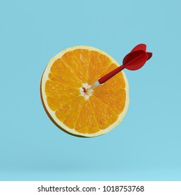 Orangefarbene Frucht mit kreisförmigem Ziel, gekennzeichnet und roter Dart auf pastellblauem Hintergrund. Minimales Konzept von Essen und Obst. Eine Idee, die kreativ ist, Arbeit in Werbe-Marketingkommunikation zu produzieren 
