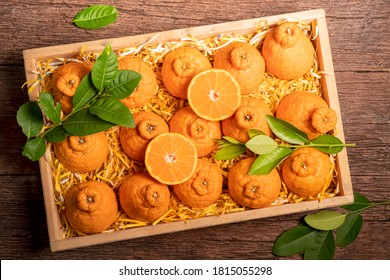 Orange Fruit With Orange Slices And Leaves In Wooden Box, Dekopon Orange Or Sumo Mandarin Tangerine With Leaves In Box Packaging.