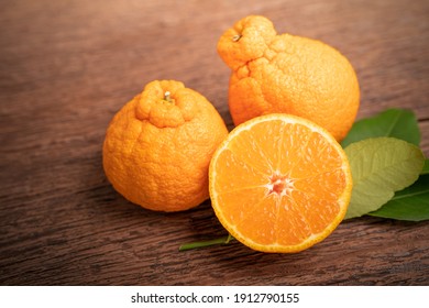 Orange Fruit With Orange Slices And Leaves In Wooden Background, Dekopon Orange Or Sumo Mandarin Tangerine With Leaves On Wooden Background.