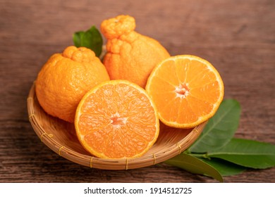 Orange Fruit With Orange Slices And Leaves In Wooden Background, Dekopon Orange Or Sumo Mandarin Tangerine With Leaves On Wooden Background.