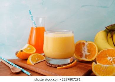 Orange fruit smoothie in a glass with fresh orange slices on wooden background