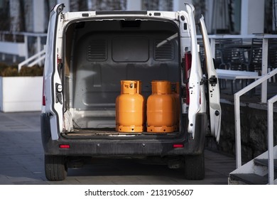 Orange gas cylinders transported inside a pickup car. Gas butane bottles in truck ready for delivery. Vehicle delivering hazard goods with compressed gas.