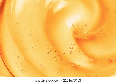 Orange gel texture background. Gold cosmetic transparent cream swirl with bubbles. Citrus fruit skincare product closeup