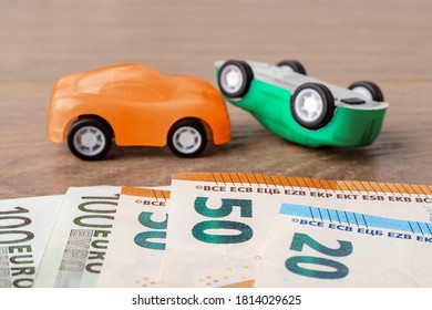 Orange And Green Toy Car Crush Accident And Different Euro Banknotes. Concept Of Car Buying, Renting, Service, Repair And Insurance Costs. Planning For Expenses. Front View.