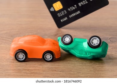 Orange And Green Toy Car Crush Accident And Credit Card. Concept Of Car Buying, Renting, Service, Repair And Insurance Costs. Planning For Expenses. Front View.