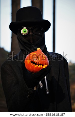 Orange Halloween Pumpkin In The Hand Of School Boy In The Black Coat And Black Bowler Hat.