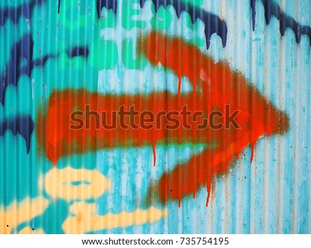 Orange hand spraying big right arrow on dirty green blue painted iron metal corrugated sheet wall background