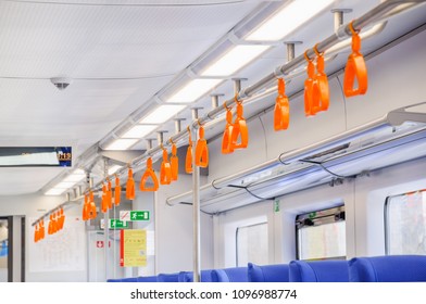 Orange hanging handholds for standing passengers in a modern train. Suburban and urban transport