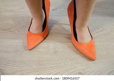 Orange Hiccups Woman Shoes On A Tiny Baby Girl Feet On A Hardwood Floor