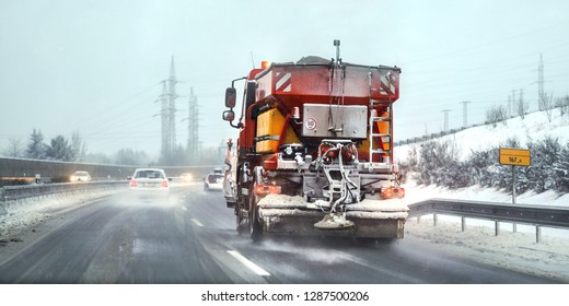 Orange Highway Maintenance Gritter Truck Spreading De Icing Salt On Road. Dangerous Driving Conditions