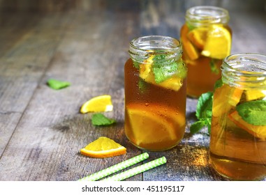 Orange Iced Tea In A Glass Jar On A Rustic Wooden Background.