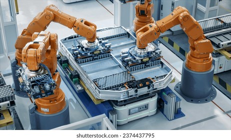 Orange Industrial Robot Arms Assemble Skateboard style EV Battery Pack on Automated Production Line. Electric Car Smart Factory Equipped with Robotic Arms. Battery Module Installation Process Top View