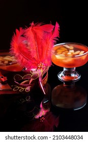 Orange Jello On A Beautiful Bowl With Fruit Pieces Inside. Black Background, Decorated With Pink Feathers.