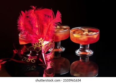 Orange Jello On A Beautiful Bowl With Fruit Pieces Inside. Black Background, Decorated With Pink Feathers.