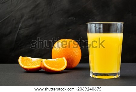orange juice with fresh orange and sliced wedges on a dark background, fortified drink rich in vitamin C