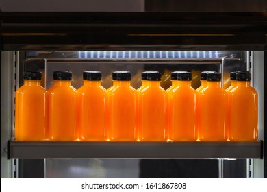 Orange juice glass bottles ice cold with tasty drink on freezer shelves. Concept of squeezed fruit juice for health and freshness