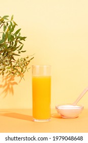 Orange Juice Glass And Collagen Powder On Table With Plant