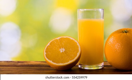 Orange juice in glass and oranges outdoors on wooden table