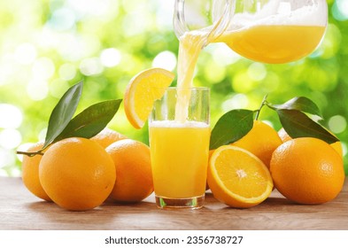 Orange juice pouring into glass. Glass of orange juice and fresh fruits on wooden table - Powered by Shutterstock