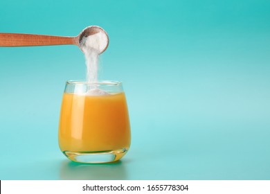 Orange juice with spoon of protein or collagen. Food supplement concept