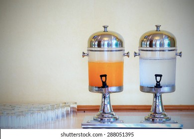 Orange Juice And Water In Dispenser And Glasses On Table For Party