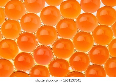 Orange juicy gel balls. Imitation yolk. Macro of hydrogel. Abstract wallpaper of 3d round pattern. Summer bright background