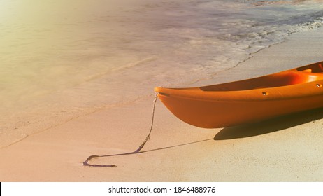 Orange Kayak boat at the side of the tropical sand beach island in Malaysia with sun flare light. Travel and tourism concept in Southeast Asia. Wallpaper, brochure, banner, poster, flyer and template.