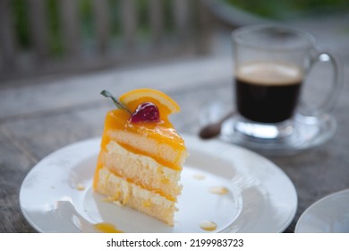 Orange Layer Cake On Top With A Red Cherry And A Cup Of Coffee