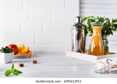 Orange lemonade in the decanter on a wooden tray and Cocktail shaker for preparing a summer cocktail with a place for your subject and text